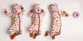 Load image into Gallery viewer, Three babies in matching Jammie Session Doughzing Off Rompers and headbands lie on a plain background, reaching for a pink frosted donut.