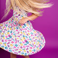 Load image into Gallery viewer, A child twirls in the Big Dreams Little Jammies Block Party (Purple) Short Sleeve Big Kid Twirl Dress, her blonde hair flying, while the hypoallergenic bamboo fabric keeps her comfy and stylish all day.