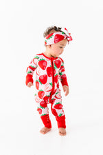 A toddler in a Jammie Session Berry Sweet (Strawberry) Romper with a matching headband stands against a plain white background.