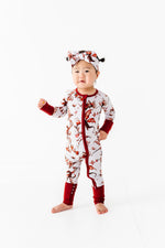A young child stands barefoot against a white background, wearing the Jammie Session Dreaming with Dragons Romper and a matching headband.