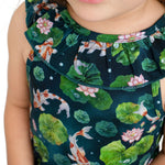 Close-up of a child wearing the Jammie Session Bundle of Koi Bloomy Crop Set, a sleeveless dark green outfit featuring koi fish, lily pads, and pink water lilies. The child's face is partially visible.
