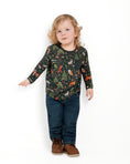 Load image into Gallery viewer, A young child with curly blond hair stands against a white background, wearing the Jammie Session "Wood you be my friend" Kids' Long Sleeve T-shirt, paired with blue jeans and brown shoes.

