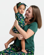 A woman smiles while holding a toddler, both wearing matching Jammie Session Bundle of Koi Women's Solid Short Sleeve T-shirts, combining comfort and style against a plain white background.