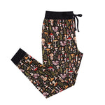 The Jammie Session Mystic Mushrooms Women's Jogger Pants feature a soft black fabric with an elastic waistband, drawstring, and colorful mushroom and foliage pattern—perfect for stylish, comfortable lounging at home.