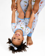 An adult holds a smiling child upside down by the hands. Both wear matching Jammie Session “Don’t Worry, Be Hoppy (Rabbit)” short pajama sets, which are hypoallergenic and ideal for sensitive skin.