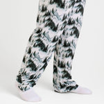 A person wears Jammie Session's Mountain Mist Men's PJ Pants, featuring a soft forest print and made from viscose from bamboo, along with white socks, standing against a plain white background.