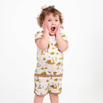 A young child in the Jammie Session "Oh Bother, It's Bedtime" Short Pajama Set—matching buttery soft bamboo shorts and t-shirt—stands hands on cheeks, open-mouthed with surprise against a white background.